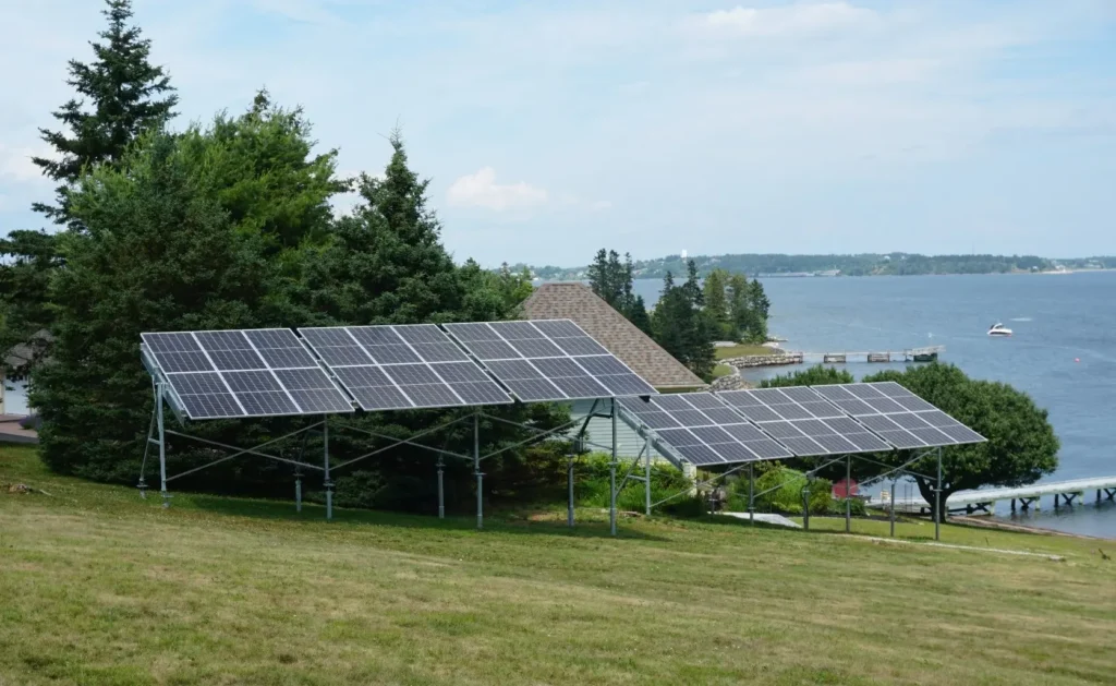 Ground-mounted array of two rows of solar panels installed near a lakefront property, demonstrating large-scale Solar Energy in Nova Scotia.